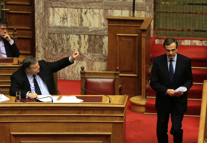 Leader of conservative New Democracy party Samaras leaves a podium as Finance Minister Venizelos raises his hand during a parliament session in Athens